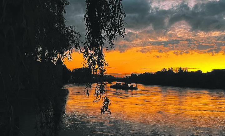 Abendstimmung an der Rheinpromenade in Rheinfelden: Auf dem Rhein sieht man den Ponton, der für den Probeaushub im Zusammenhang mit der Leistungssteigerung des Kraftwerks Rheinfelden im Einsatz war. Foto: Valentin Zumsteg