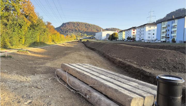 Ein Bagger trägt die Humusschicht ab. Links der Fussweg entlang der Sissle, wo künftig auch der Radweg durchführen wird.