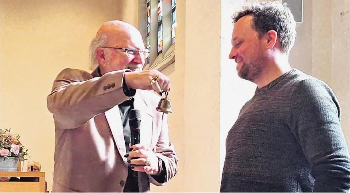 Achim Roloff (links) überreicht seinem Nachfolger Roland Arnold sein «Sitzungs-Glöcklein». Foto: zVg