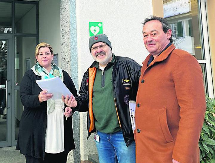 Gemeindeschreiberin Daniela Hunziker nimmt von Thomas Börlin die Unterschriften gegen das Mehrzweckhallen-Projekt entgegen; rechts im Bild: Thomas Herzog, ebenfalls Gegner des Projekts. Foto: Ronny Wittenwiler