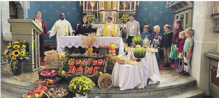 Das Liturgieteam mit den Erst- und Zweitklässlern vor den kunstvoll zubereiteten Erntegaben. Foto: zVg