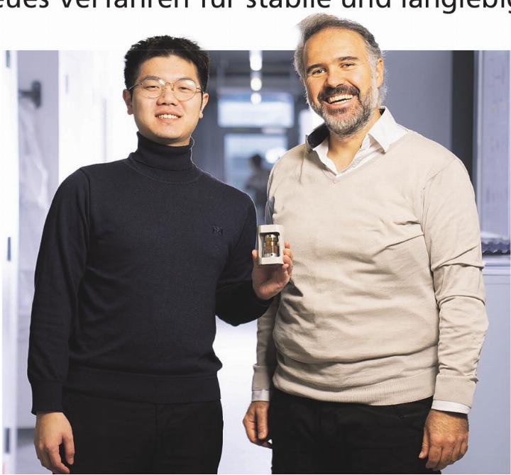 Jinsong Zhang (links) und Mario El Kazzi mit einer Testzelle der am Paul Scherrer Institut PSI entwickelten Festkörperbatterie. Die beiden Forscher haben ein Verfahren entwickelt, das mildes Sintern mit einer ultradünnen Lithiumfluorid-Beschichtung kombiniert und so besonders stabile Festkörperelektrolyte ermöglicht. Foto: zVg