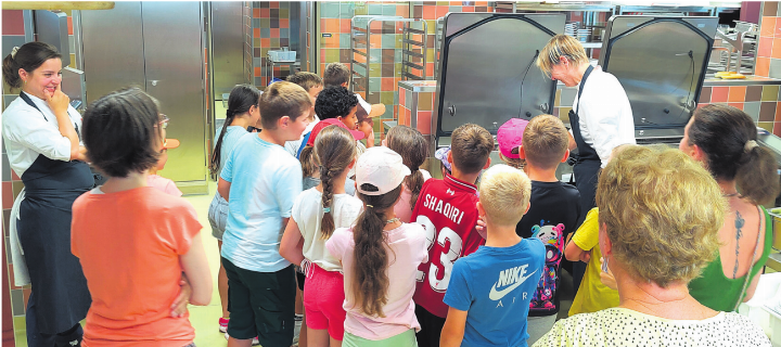 Beim Besuch am Forschungsinstitut für biologischen Landbau (FiBL) entdeckt die zweite Primarschulklasse aus Eiken mit Léa Barth (links im Bild) die Küche und blickt in die überdimensionierten Kochtöpfe, wo Trudi Hunziker-Rohrer (rechts im Bild) gerade das asiatische Linsengericht fürs Mittagessen zubereitet.    Foto: zVg
